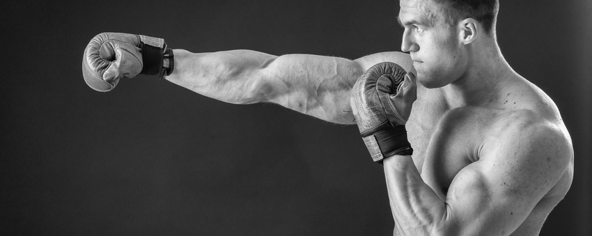 The man in boxing gloves. Young Boxer fighter over black background. Boxing man ready to fight. Boxing workout muscle strength power - the concept of strength training and boxing